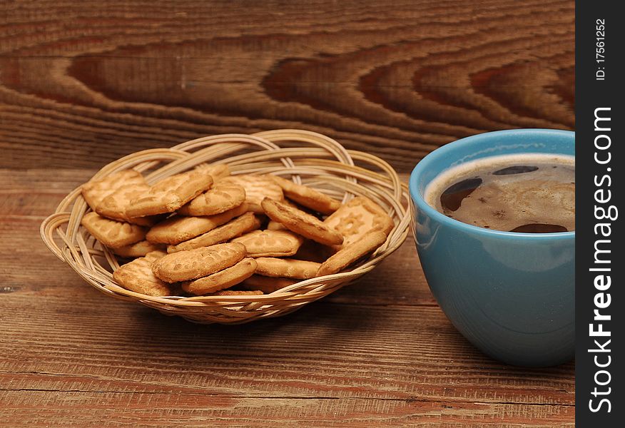 Cup of tea and cookies in basket on wood background