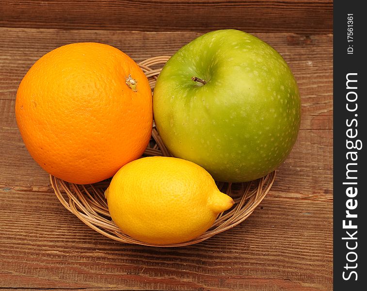 Fresh fruit in basket on wood background