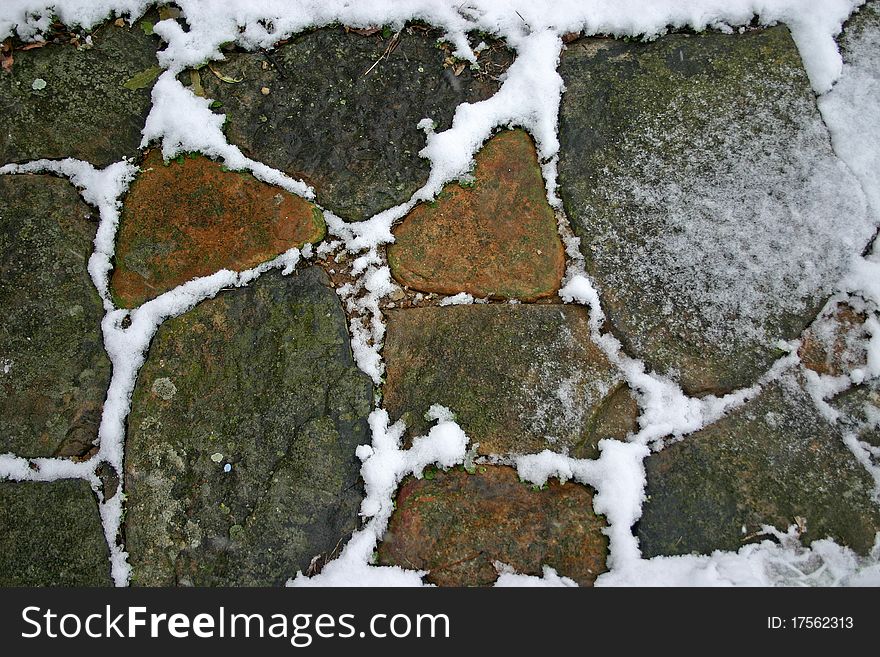 Fresh snow in between the rocks on a stone sidewalk. Fresh snow in between the rocks on a stone sidewalk