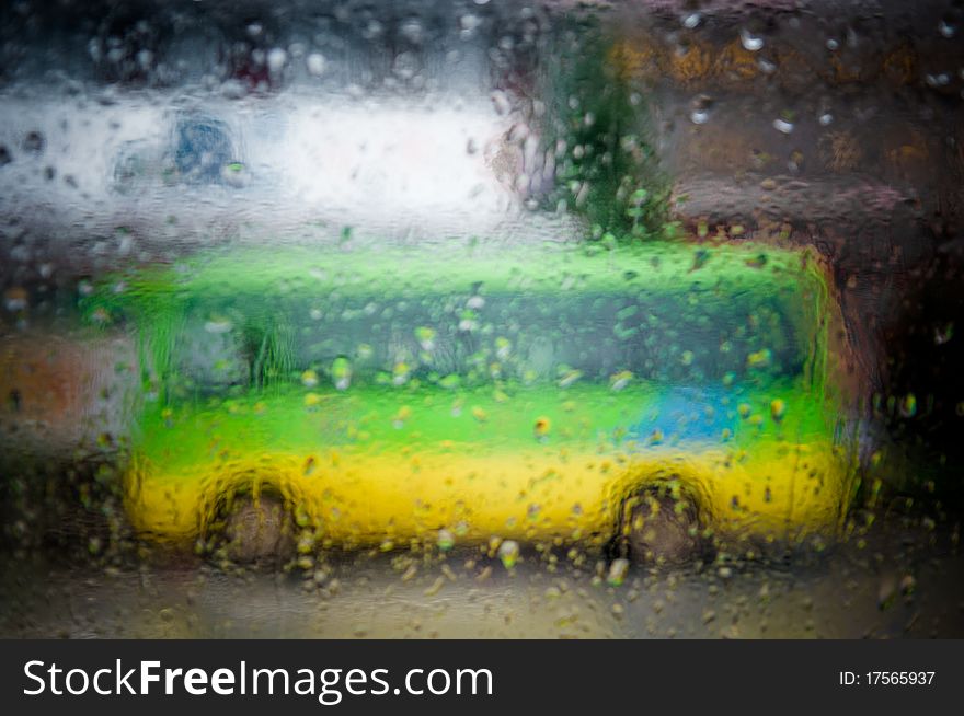 A shot of a bus through a window on a rainy day.