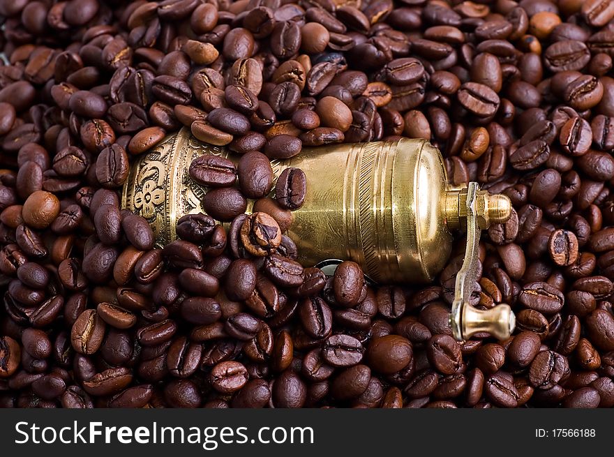 Ancient gold coffee grinder in coffee beans close up.