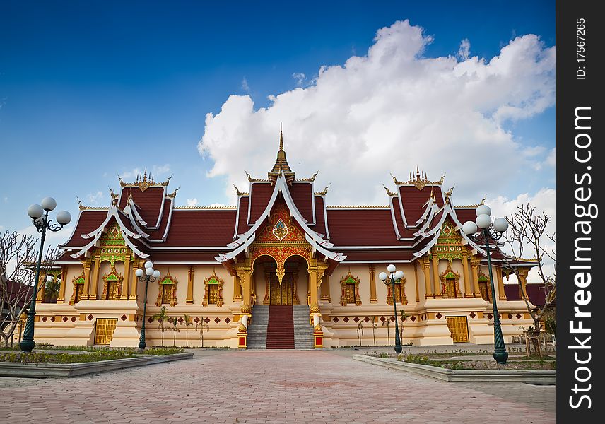 The Buddhist sanctuary in front of blue sky and white cloud with brick pathway foreground.