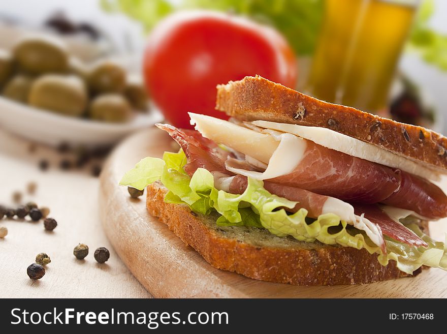 Prosciutto and cheese sandwich with olives and lettuce.