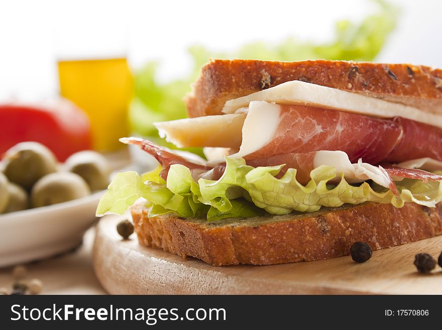 Prosciutto and cheese sandwich with olives and lettuce.