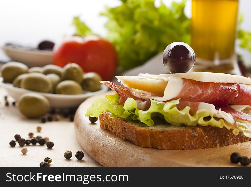 Prosciutto and cheese sandwich with olives and lettuce.Focus is on the cheese. Shallow depth of field.