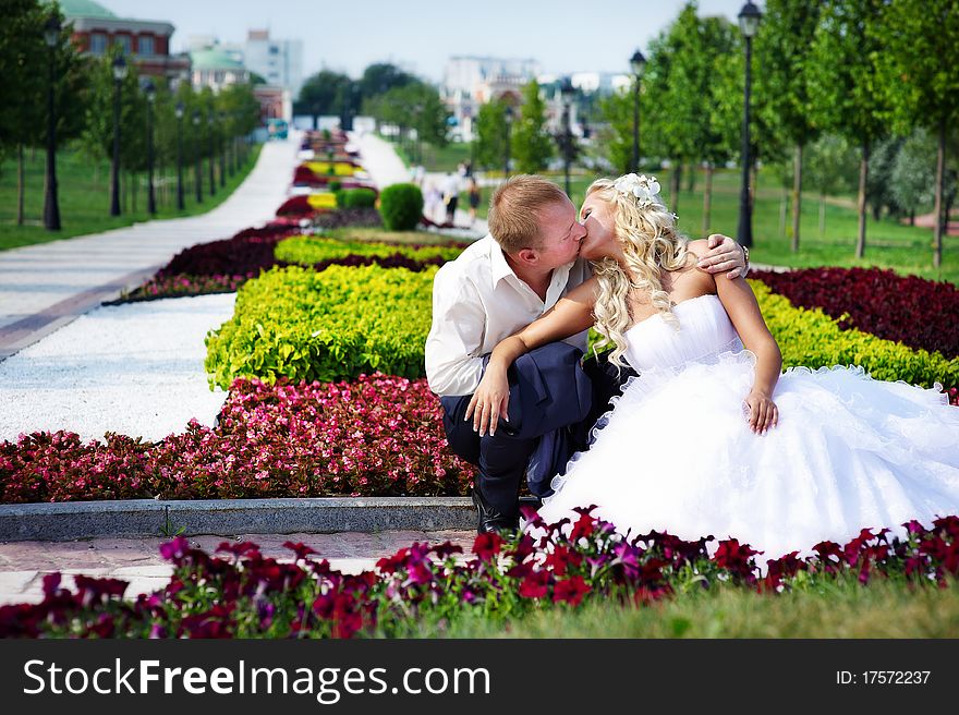 Happy bride and groom at a wedding a walk in the park surrounded by flowers. Happy bride and groom at a wedding a walk in the park surrounded by flowers