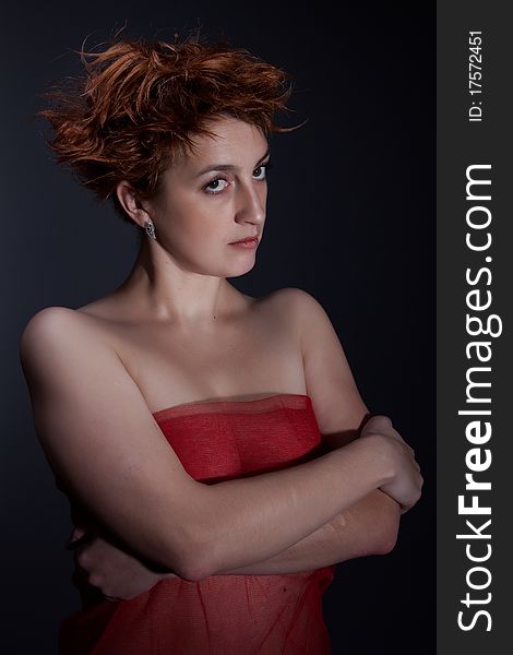 Portrait the red girl against a dark background dressed in a red