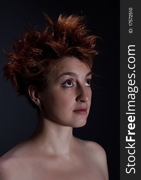 Portrait the red girl against a dark background dressed in a boa