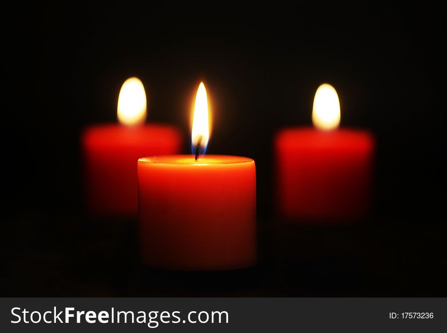 Three Red candles lit against black