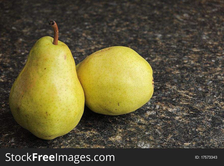 A pair of pears on a black kitchen countertop