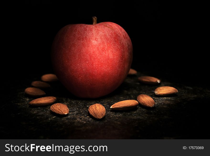 Healthy apple in the middle of a arranged circle of nuts. These fruits are being illuminated by long exposure and a light painting. Healthy apple in the middle of a arranged circle of nuts. These fruits are being illuminated by long exposure and a light painting