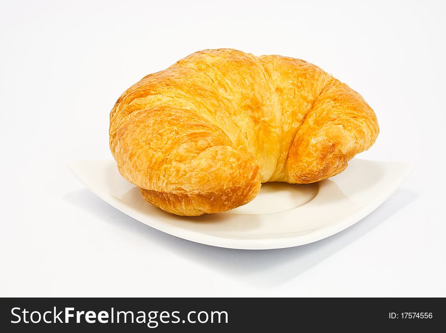 Single fresh croissant, casting soft whadow on white. Delicious!