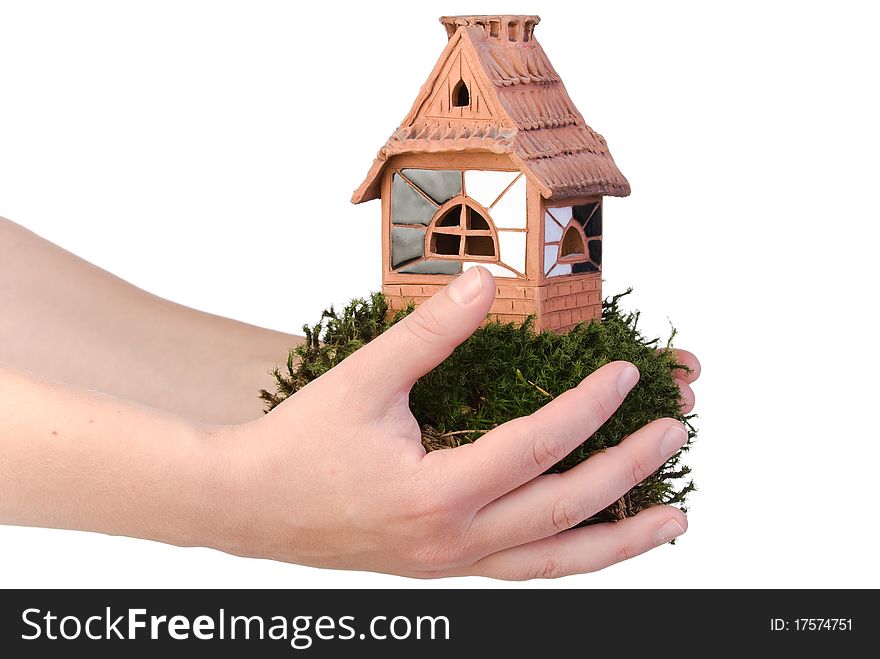 Clay house on moss in hand over white. Clay house on moss in hand over white