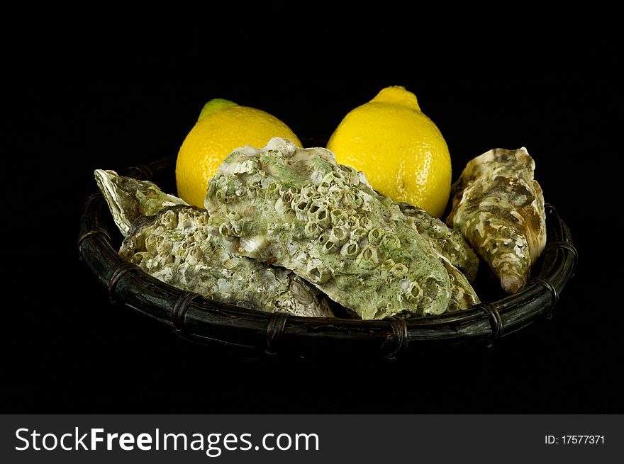 Oysters and lemons in a basket on black background