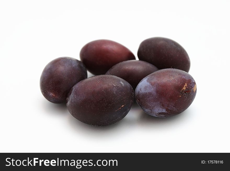 Six blue plums on a white table