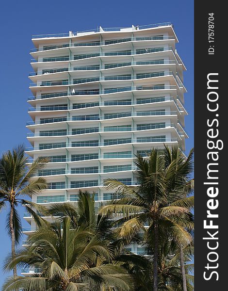 Exterior of condominium building at resort in Puerto Vallarta, Mexico, with palm trees and blue sky. Exterior of condominium building at resort in Puerto Vallarta, Mexico, with palm trees and blue sky.