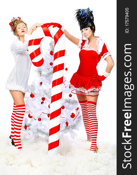 Two beautiful young women in Christmas clothes posing with a big candy. Two beautiful young women in Christmas clothes posing with a big candy.