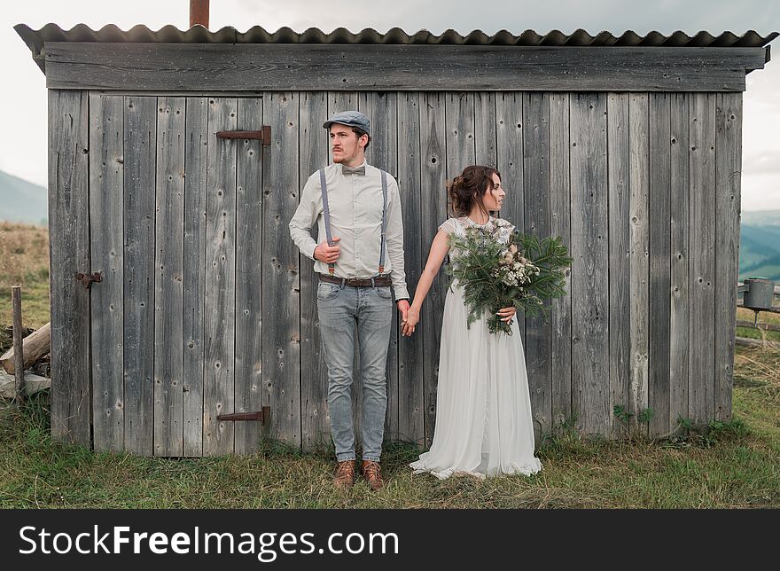 Newlyweds dressed in vintage style near gray wooden wall