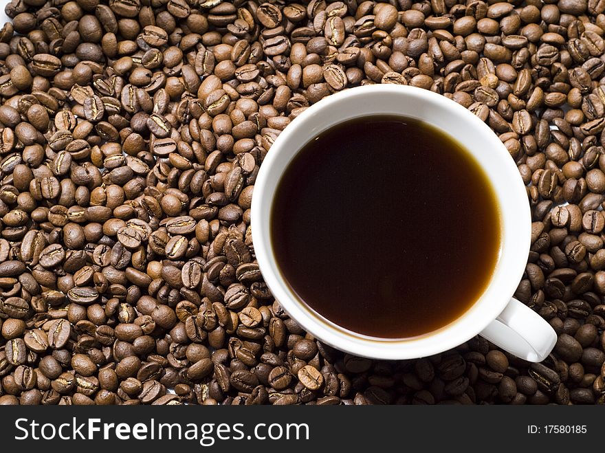 Cup of black coffee with a scattering of large grains. Cup of black coffee with a scattering of large grains
