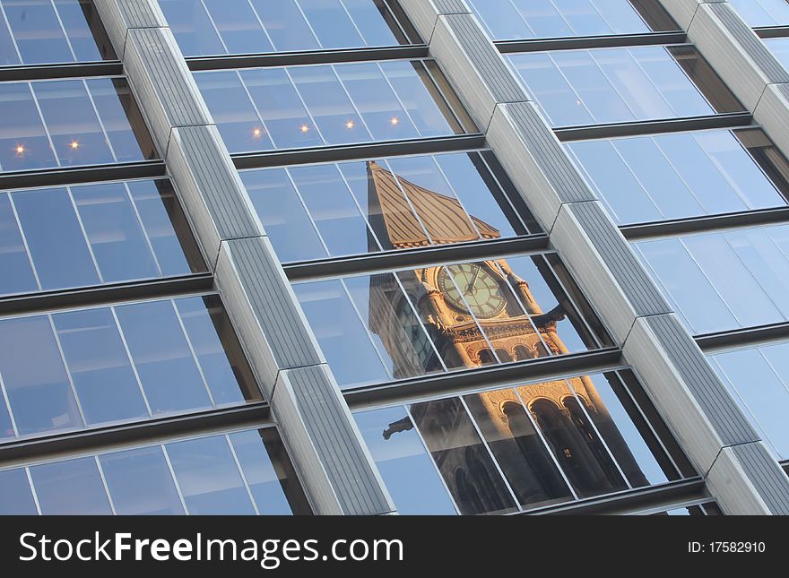 Reflection of old city hall in the windows of a modern office building