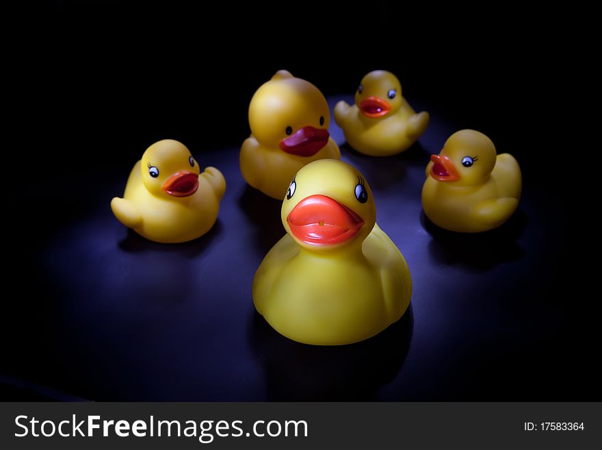 Five lightpainted rubber ducks on a black background.