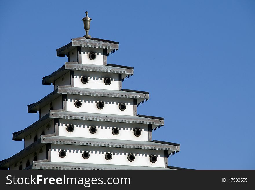 Bird house pagoda in clear blue sky.
