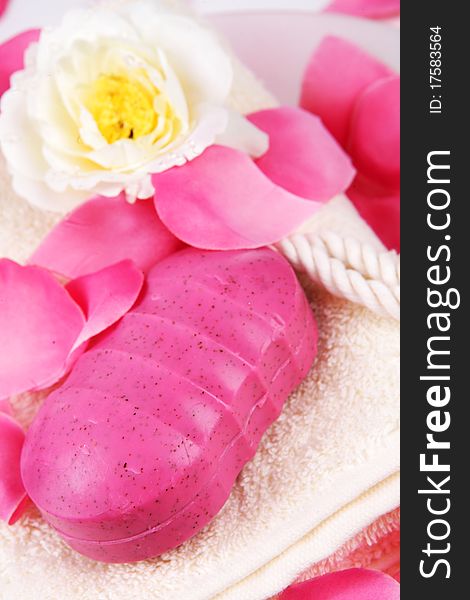 Pink hand made soap and pink rose petals on a white towel. Pink hand made soap and pink rose petals on a white towel