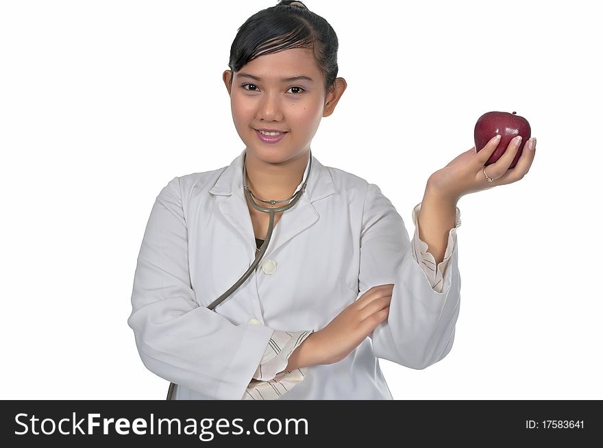 Beautiful young doctor wearing white coat holding red apple isolated over white background. Beautiful young doctor wearing white coat holding red apple isolated over white background