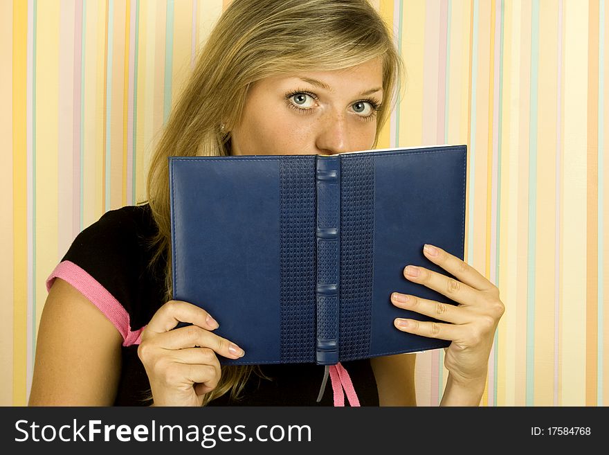 Young beautiful girl in the room face covered notebooks. Young beautiful girl in the room face covered notebooks