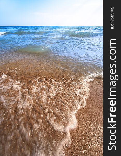 Beach pebbles under clear water with waves