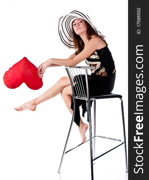 Beautiful young girl sitting on a bar chair with red heart pillow  isolated on white