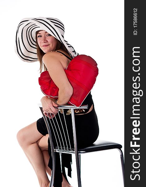 Beautiful young girl sitting on a bar chair with red heart pillow  isolated on white