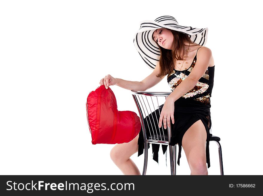 Beautiful young girl sitting on a bar chair with red heart pillow  isolated on white