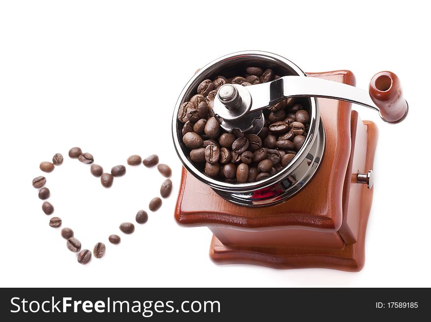 Grinder is made of brown wood, inside sprinkled coffee beans. A horizontal frame on a white background. Grinder is made of brown wood, inside sprinkled coffee beans. A horizontal frame on a white background.