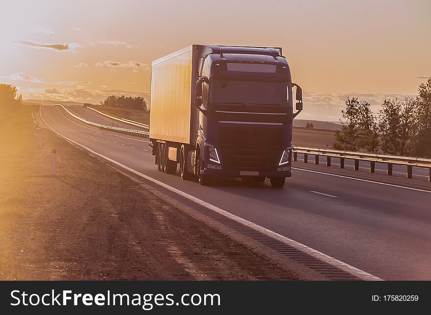 truck moves along a suburban highway at sunset lit by the sun