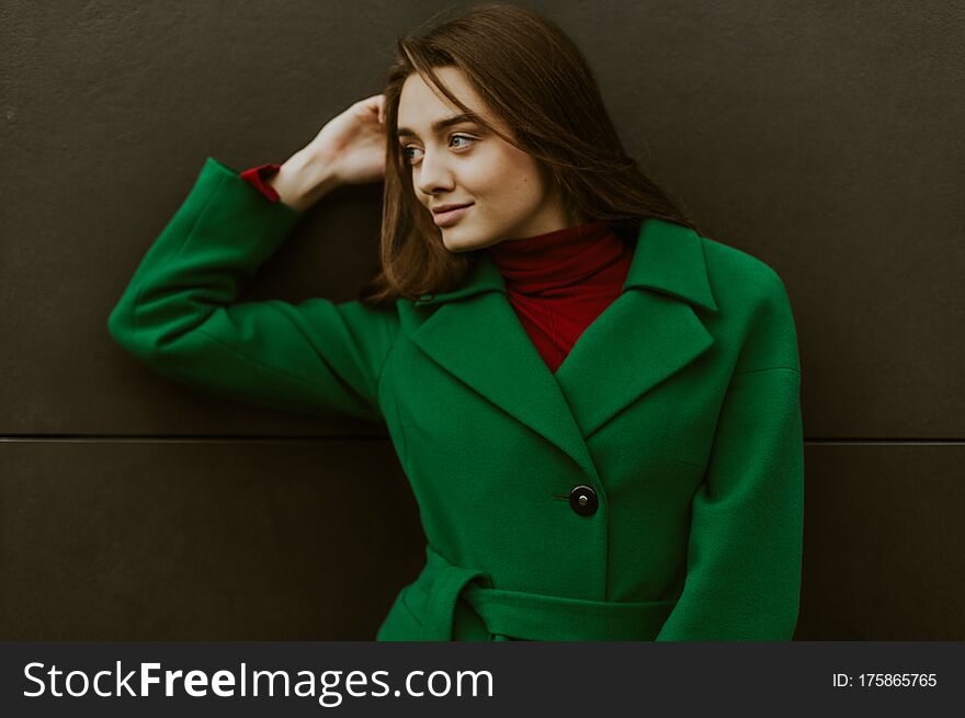 Beautiful fashion model in autumn green clothes on background. Sexy lady in elegant coat.