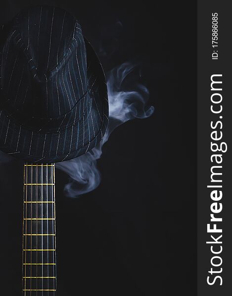 Smoking hat hangs on the guitar fretboard. acoustic musical instrument. strings on the guitar neck close up