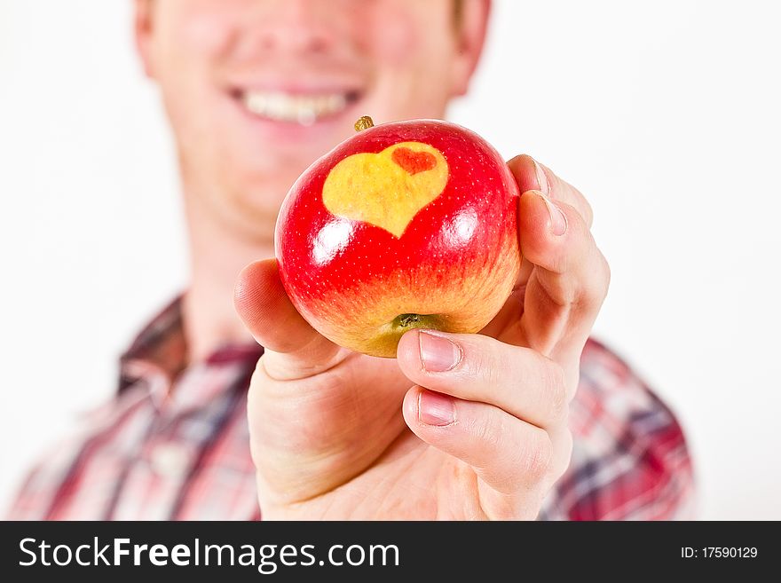 A Man is holding a red Apple with two Hearts on it. A Man is holding a red Apple with two Hearts on it