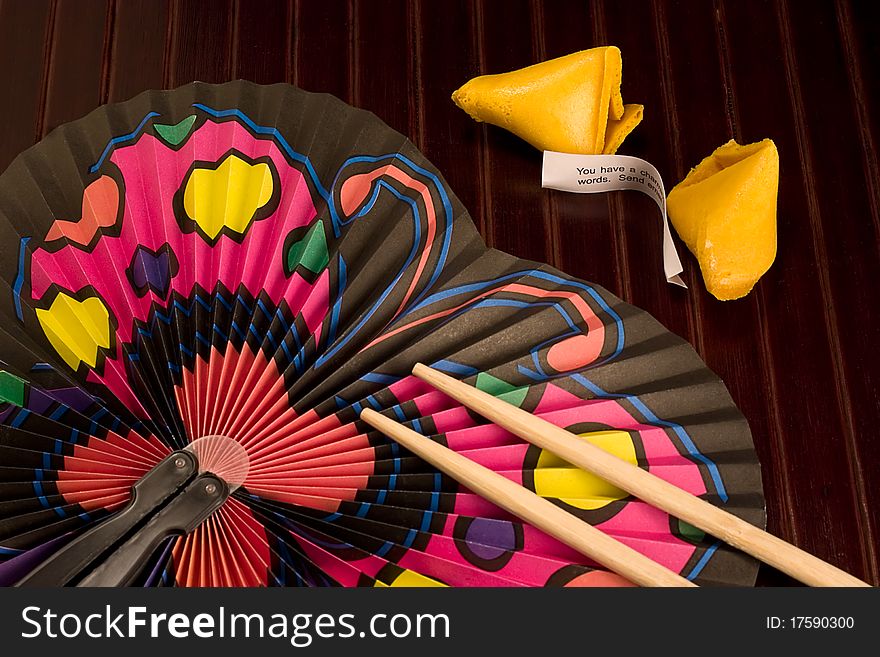 A place setting with a fan, fortune cookie and chopsticks. A place setting with a fan, fortune cookie and chopsticks.