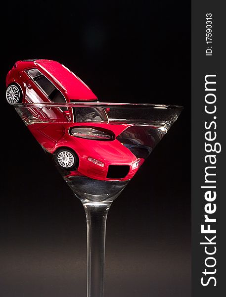 A red, toy car in a Martini glass. A red, toy car in a Martini glass.