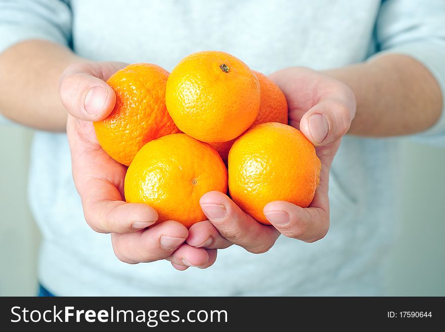 Man is holding fresh mandarins in his hands
