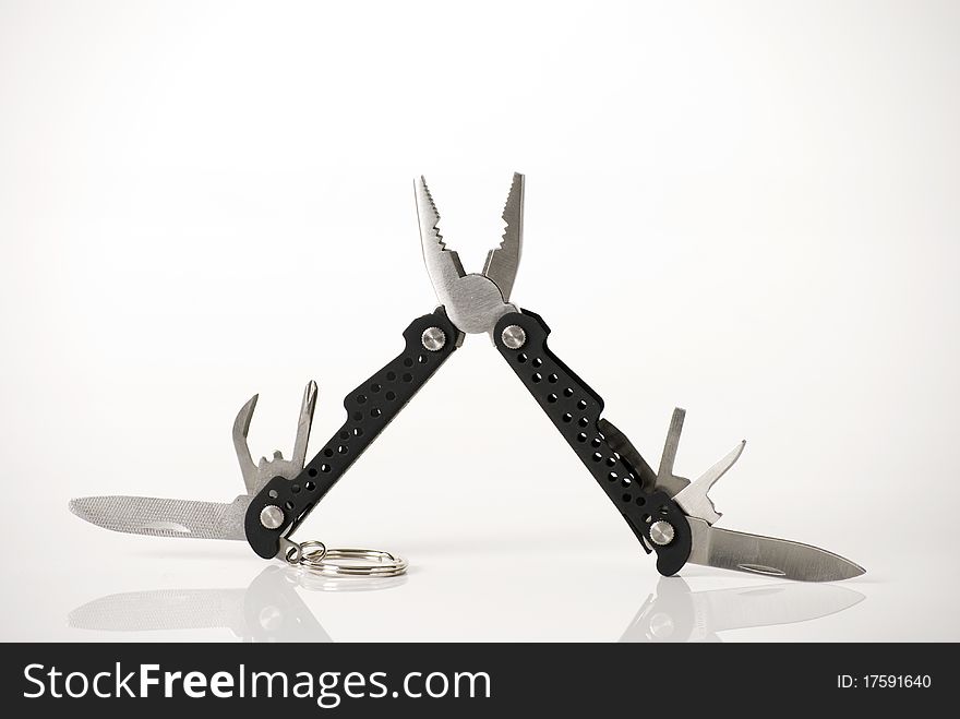 A horizontal image of a black rubber handled multitool with all blades and attachments open isolated against a white background. A horizontal image of a black rubber handled multitool with all blades and attachments open isolated against a white background