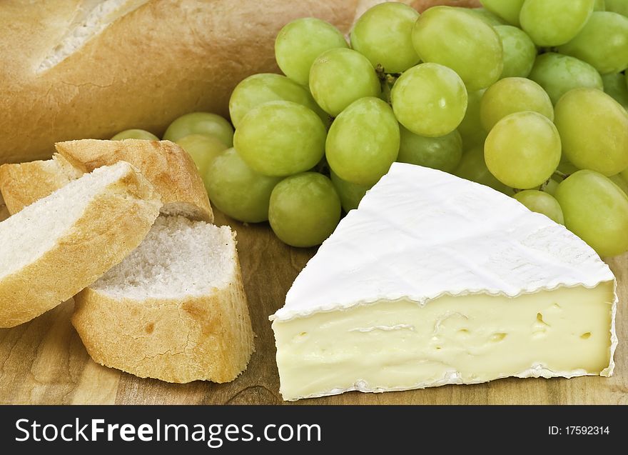 A board with cheese , bead, and grapes. A board with cheese , bead, and grapes