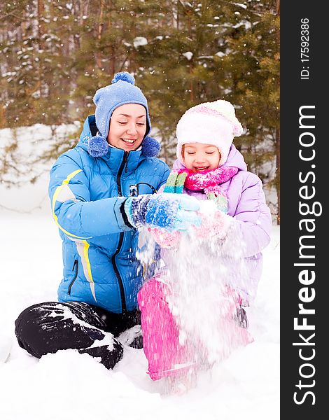 Happy family; young mother and her daughter having fun in the winter park (focus on the woman). Happy family; young mother and her daughter having fun in the winter park (focus on the woman)