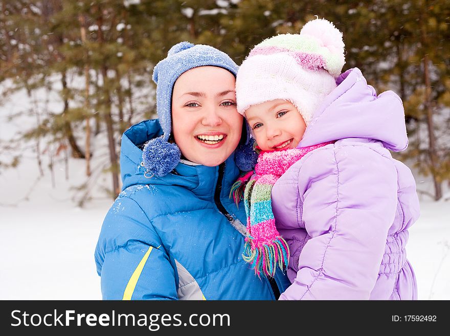 Happy family; young mother and her daughter having fun in the winter park (focus on the child). Happy family; young mother and her daughter having fun in the winter park (focus on the child)