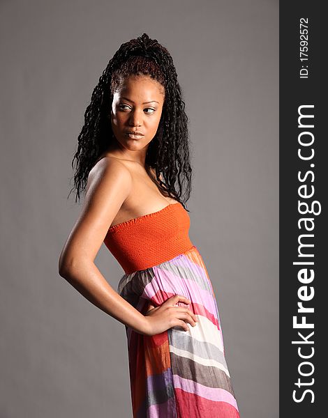 Majestic and young African American girl wearing colourful dress. Studio shot, portrait on grey backdrop. Majestic and young African American girl wearing colourful dress. Studio shot, portrait on grey backdrop.