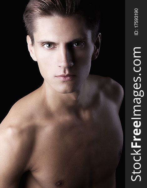 Young attractive macho with beautiful body on black background