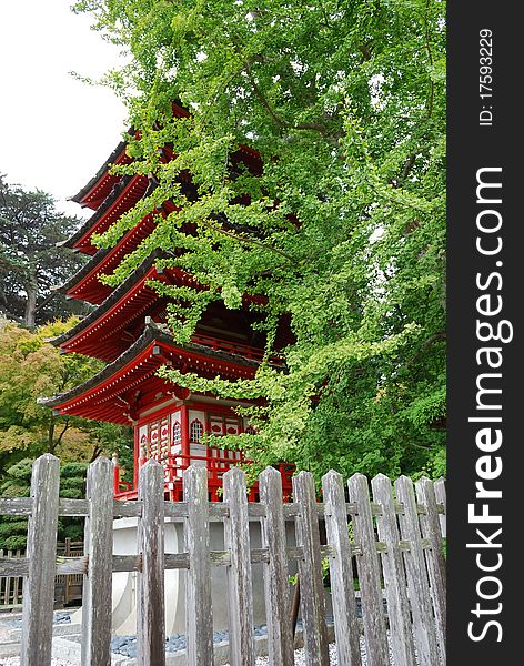 Red Japanese multistory house behind a green tree. Red Japanese multistory house behind a green tree