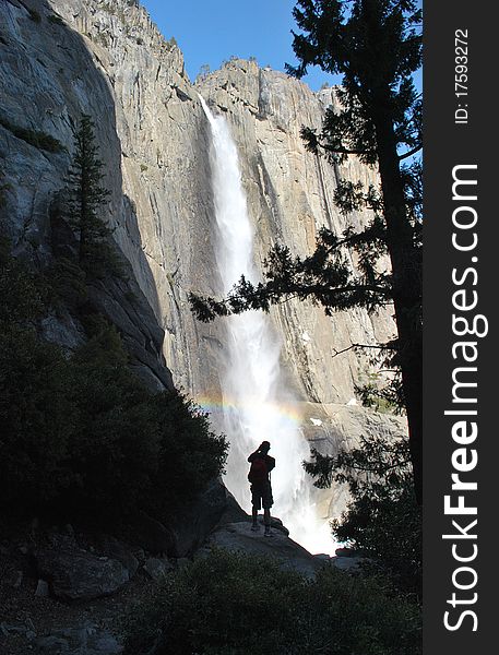 A man photographing a roaring waterfall in Yosemite. A man photographing a roaring waterfall in Yosemite