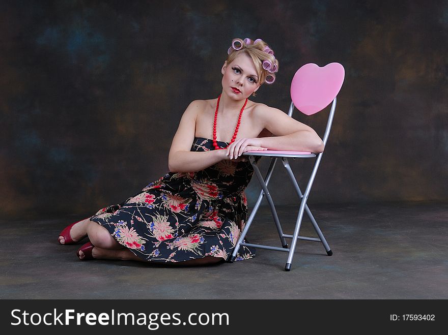 Photograph showing retro style 50s female relaxing next to stool with heart on. Photograph showing retro style 50s female relaxing next to stool with heart on